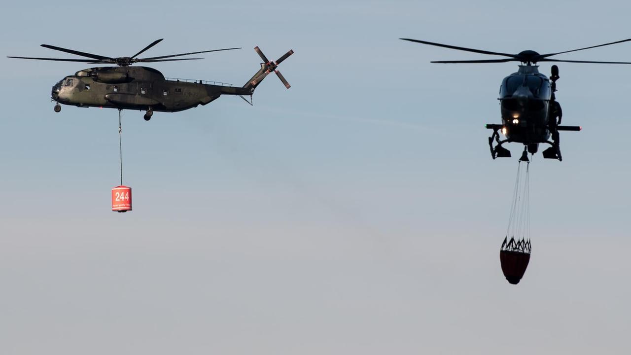 Hubschrauber der Bundeswehr mit Wasserbehältern beim Löscheinsatz in Bayern