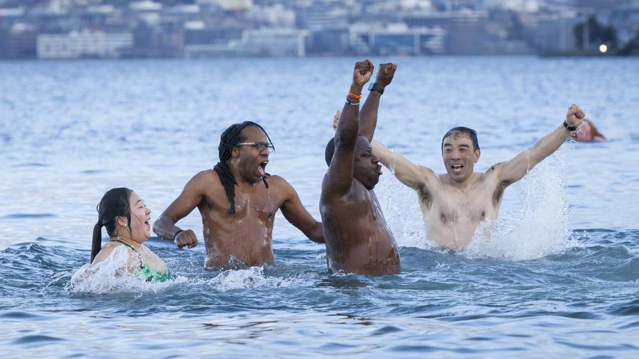 Das Foto zeigt mehrere Menschen mit unterschiedlichen Hautfarben beim Baden in kaltem Wasser.