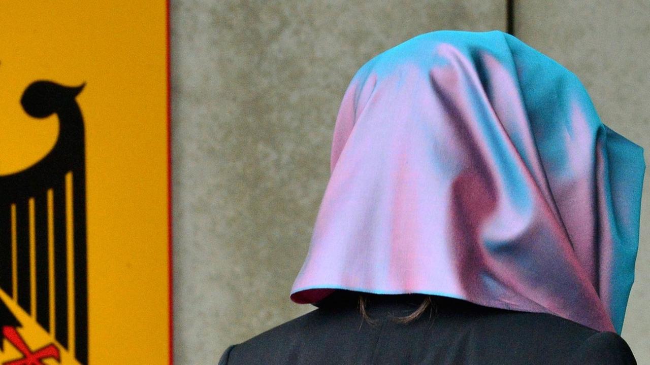 Eine junge Frau mit Kopftuch, die Klägerin, läuft am 24.09.2014 in Erfurt (Thüringen) am Behördenschild mit der Aufschrift "Bundesarbeitsgericht" vorbei. Eine junge Frau mit Kopftuch, die Klägerin, läuft am 24.09.2014 in Erfurt (Thüringen) am Behördenschild mit der Aufschrift "Bundesarbeitsgericht" vorbei.