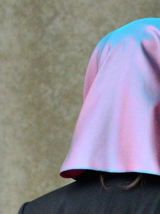 Eine junge Frau mit Kopftuch, die Klägerin, läuft am 24.09.2014 in Erfurt (Thüringen) am Behördenschild mit der Aufschrift "Bundesarbeitsgericht" vorbei.