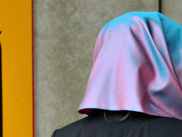 Eine junge Frau mit Kopftuch, die Klägerin, läuft am 24.09.2014 in Erfurt (Thüringen) am Behördenschild mit der Aufschrift "Bundesarbeitsgericht" vorbei.