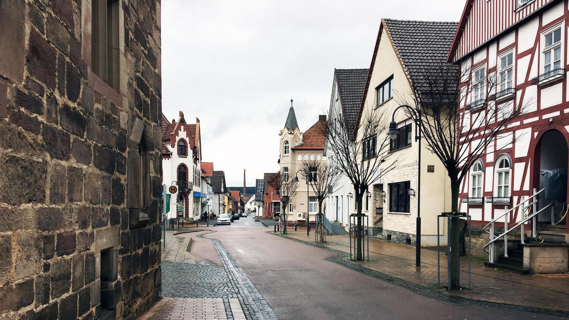 Eine Asphaltstraße führt durch ein Dorf. Das Dorf ist alt: Rechts steht ein Fachwerkhaus. Weitere historische Bauten aus dem späten Mittelater sind zu sehen.
