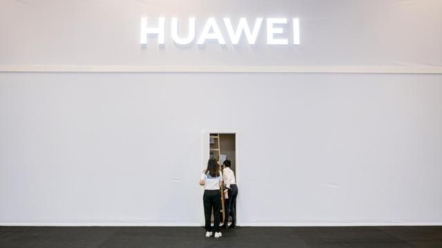 Zwei Mitarbeiter des Technologieunternehmen Huawei in der Internationalen Funkausstellung (IFA) stehen vor einem Seiteneingang des Standes.