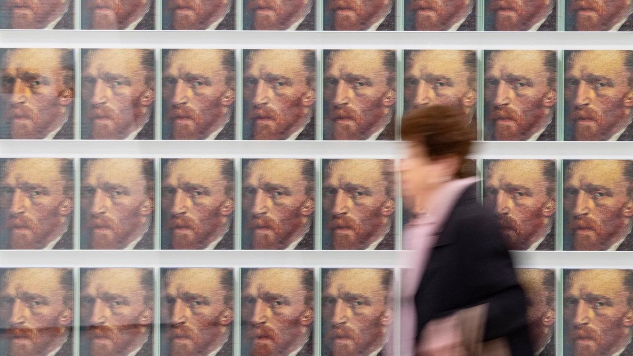 Eine Besucherin geht in der Ausstellung "Making van Gogh" an Katalogen mit einem Selbstporträt des Malers vorbei. Eine Besucherin geht in der Ausstellung "Making van Gogh" an Katalogen mit einem Selbstporträt des Malers vorbei.