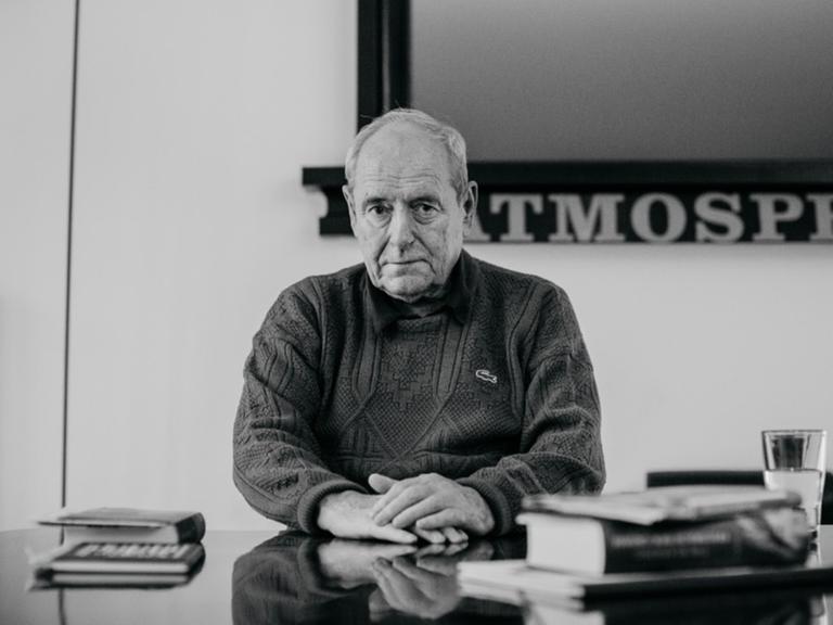 Der Kunstsammler Harald Falckenberg sitzt an einem Schreibtisch mit Büchern.