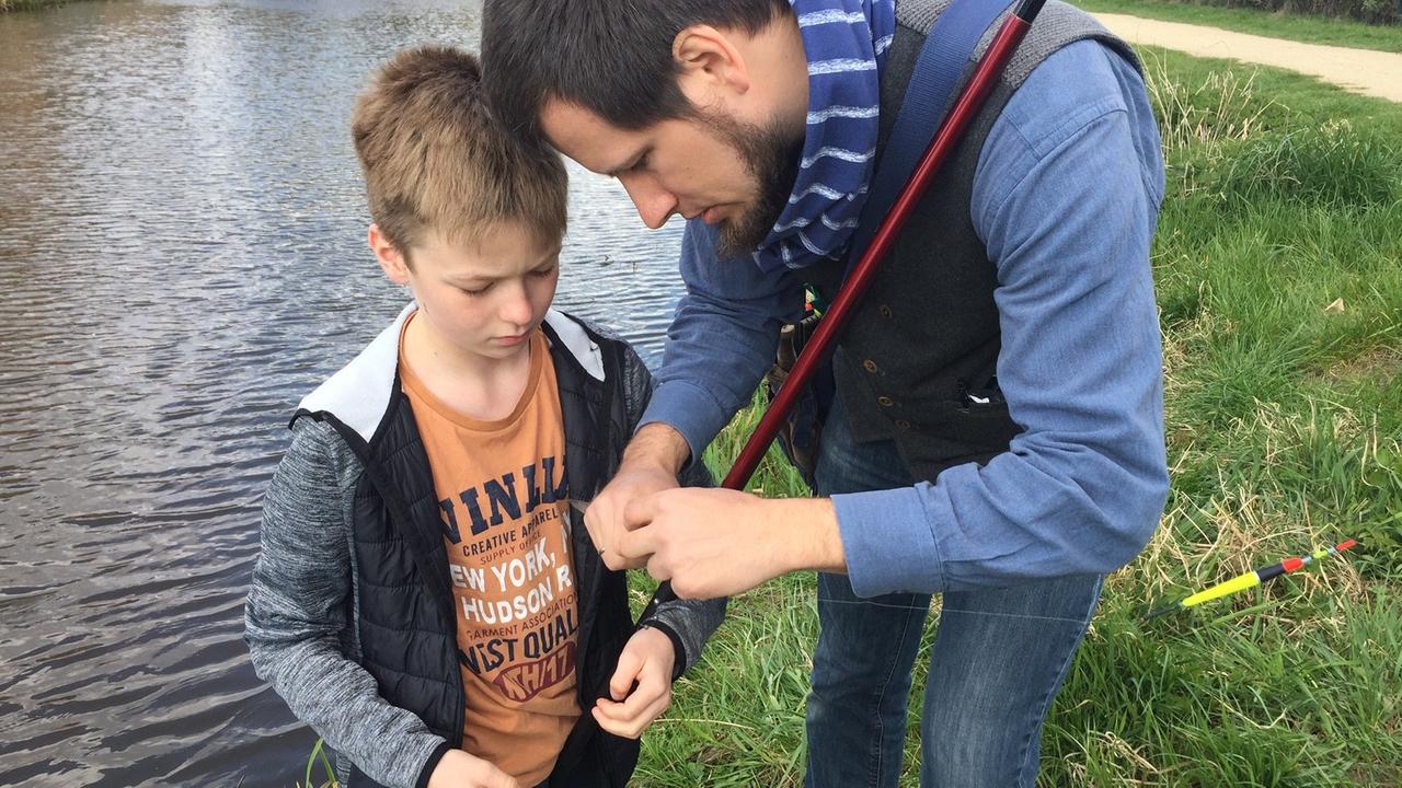 Der Sechsklässler Jannik steht an einem Ufer, neben ihn der Ausbilder Christoph Witteck, der dem Schüler etwas zeigt. Der Sechsklässler Jannik steht an einem Ufer, neben ihn der Ausbilder Christoph Witteck, der dem Schüler etwas zeigt.