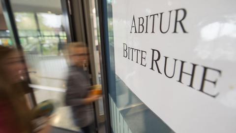 Zwei Schülerinnen gehen am 25.04.2017 im Solitude-Gymnasium in Stuttgart auf dem Weg zum Prüfungsraum an einem Schild mit der Aufschrift "Abitur - Bitte Ruhe" vorbei. (Symbolbild)
