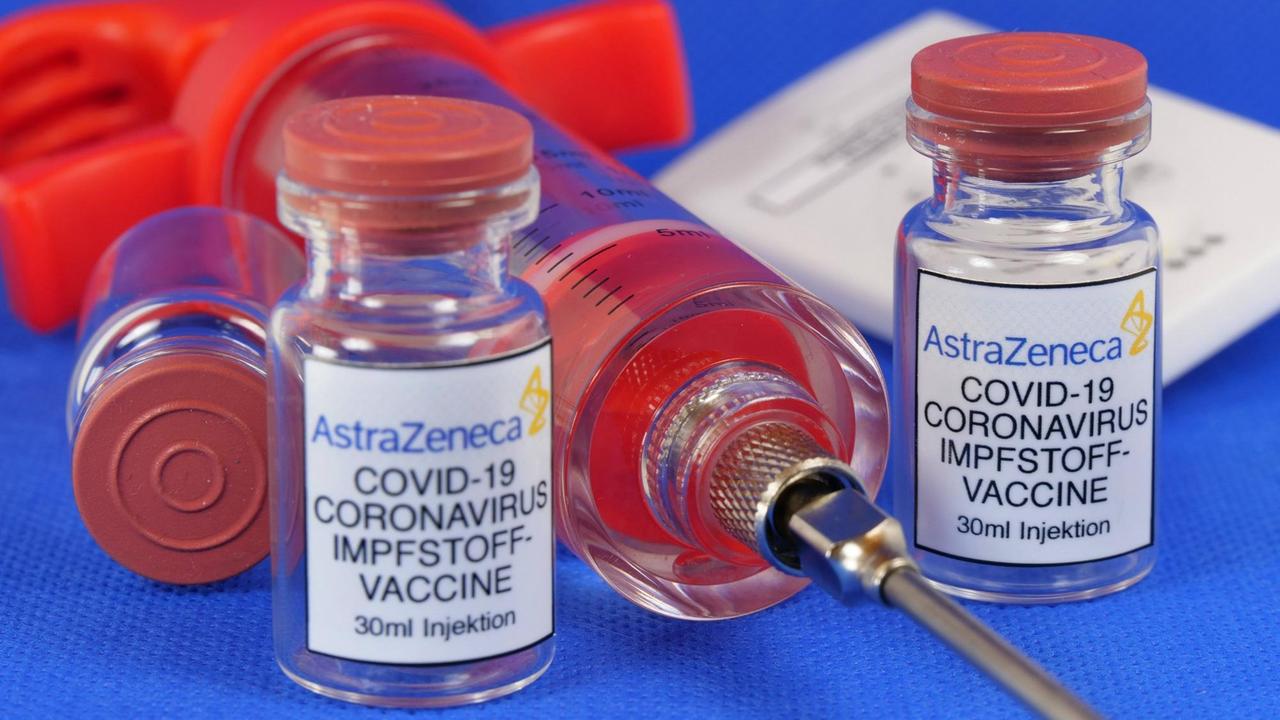 Zwei Phiolen mit dem Coronaserum-Impfstoff von AstraZeneca. Dazwischen liegt eine Spritze.