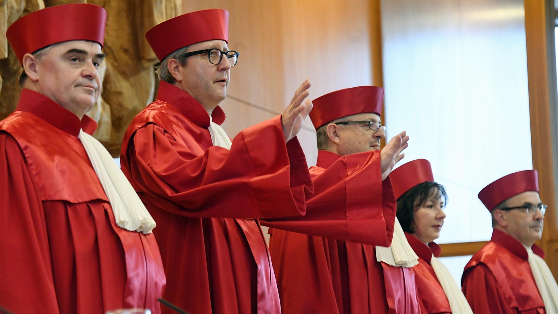 Das Bild zeigt die Richter in roten Roben nebeneinander stehen.