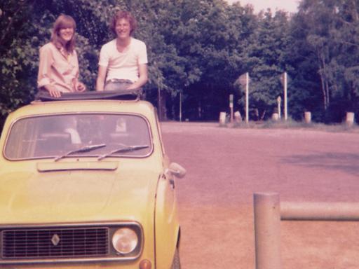 Günther Wessel mit seinem Renault 1977. Ein Pärchen schaut aus dem Dachfenster eines gelben Renaults.
