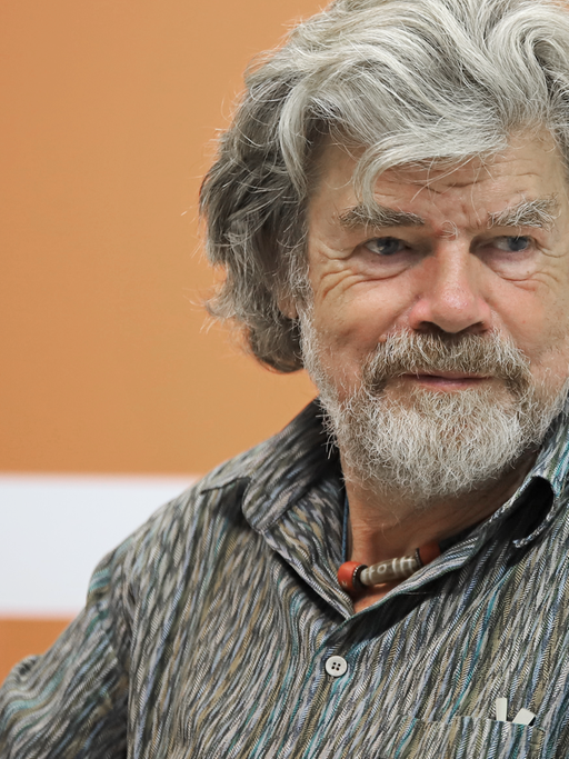 Reinhold Messner sitzt mit einem Mikro in der Hand auf einem Stuhl und spricht mit der Moderatorin der Sendung.