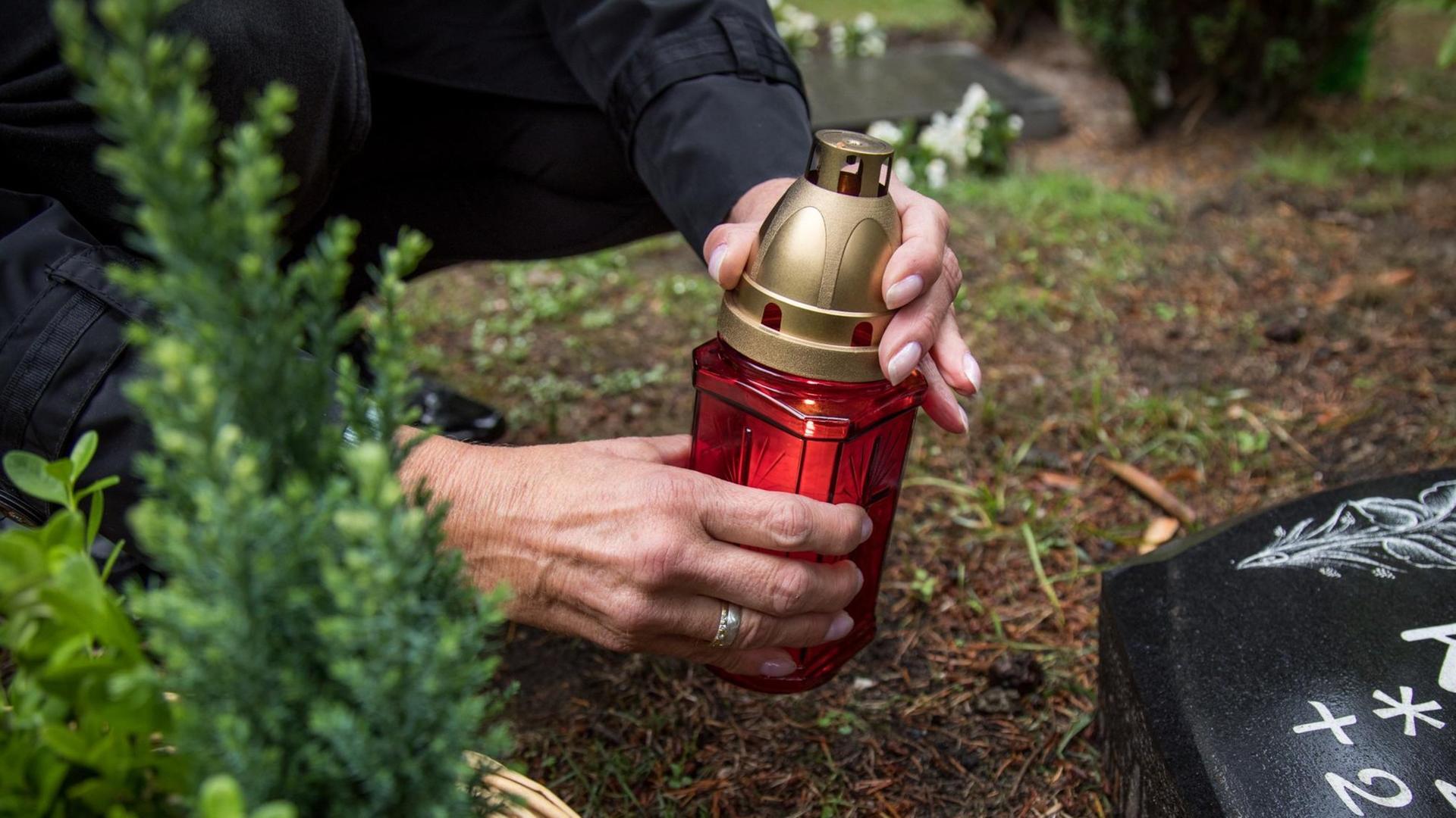 Eine Frau zündet in Hamburg auf einem Friedhof eine Kerze an. Eine Frau zündet in Hamburg auf einem Friedhof eine Kerze an.