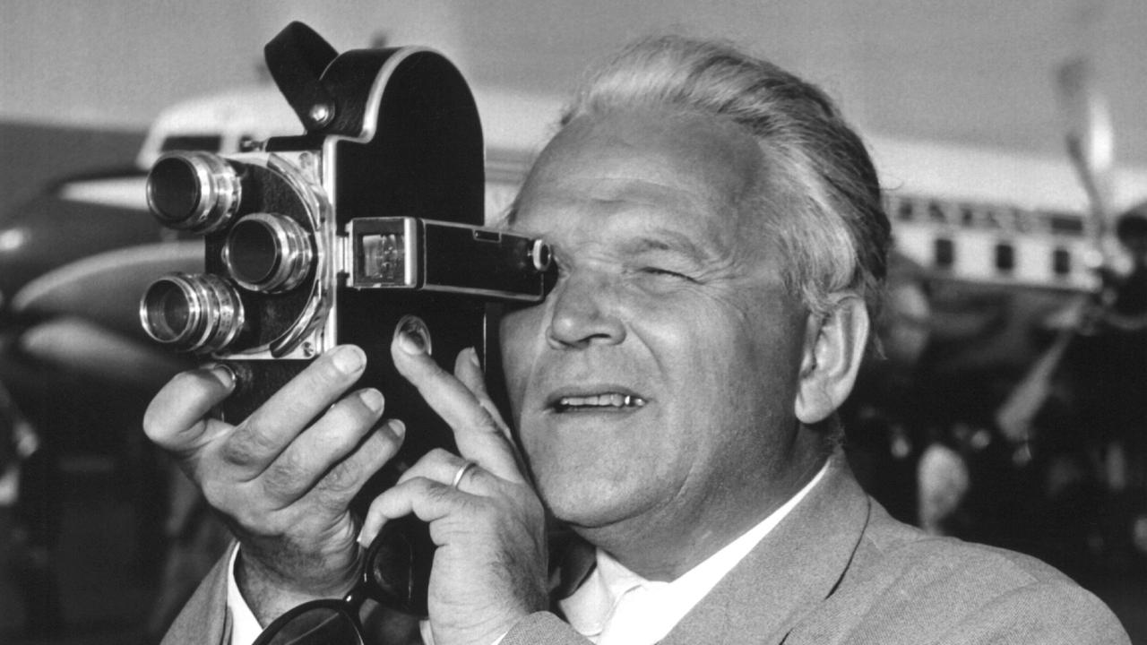 Der Filmregisseur Veit Harlan filmt 1954 auf dem Münchner Flughafen mit einer Schmalfilm-Kamera.