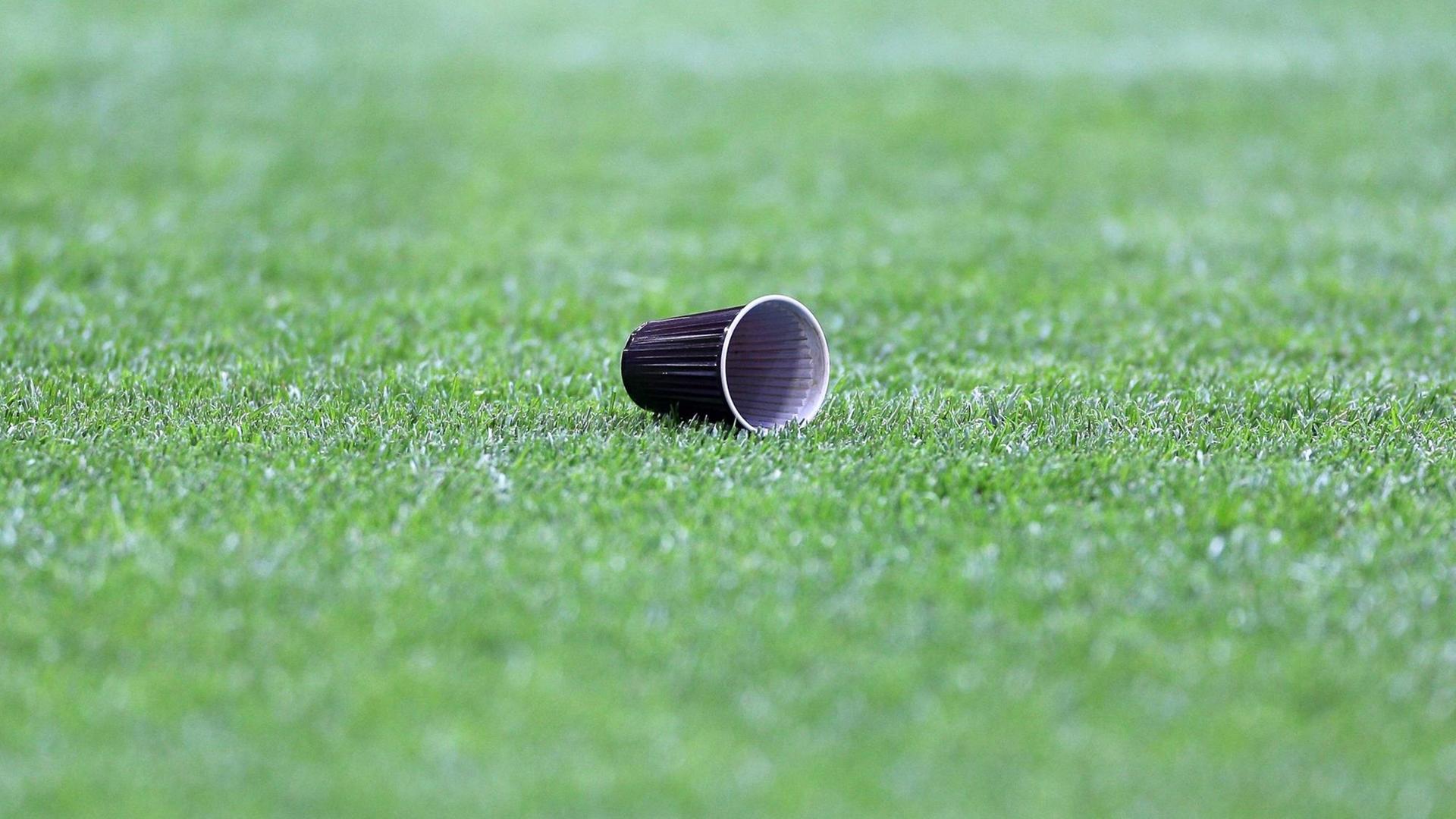Ein Plastikbecher liegt auf einem Fußballfeld. Ein Plastikbecher liegt auf einem Fußballfeld.