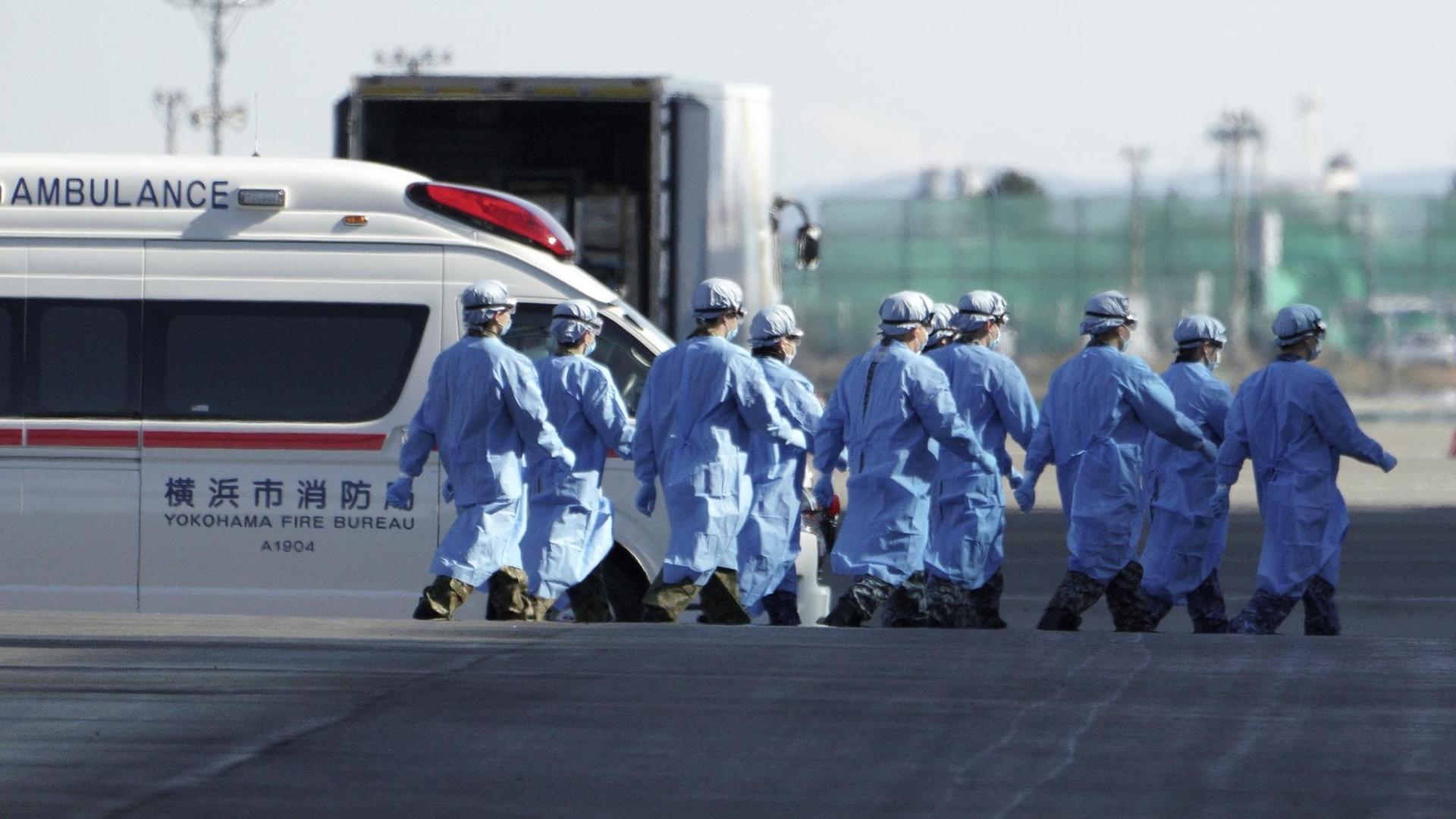 Japanische Offizielle auf dem Weg zum Kreuzfahrtschiff "Diamond Princess", das im japanischen Hafen Yokohama vor Anker liegt. Japanische Offizielle auf dem Weg zum Kreuzfahrtschiff "Diamond Princess", das im japanischen Hafen Yokohama vor Anker liegt.