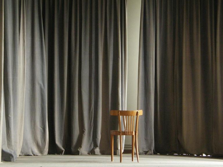 Ein leerer Stuhl steht auf einer verwaisten Bühne.