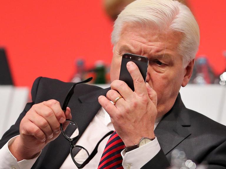 Frank-Walter Steinmeier - hier beim SPD-Bundesparteitag 2013 - blickt am auf sein Mobiltelefon.
