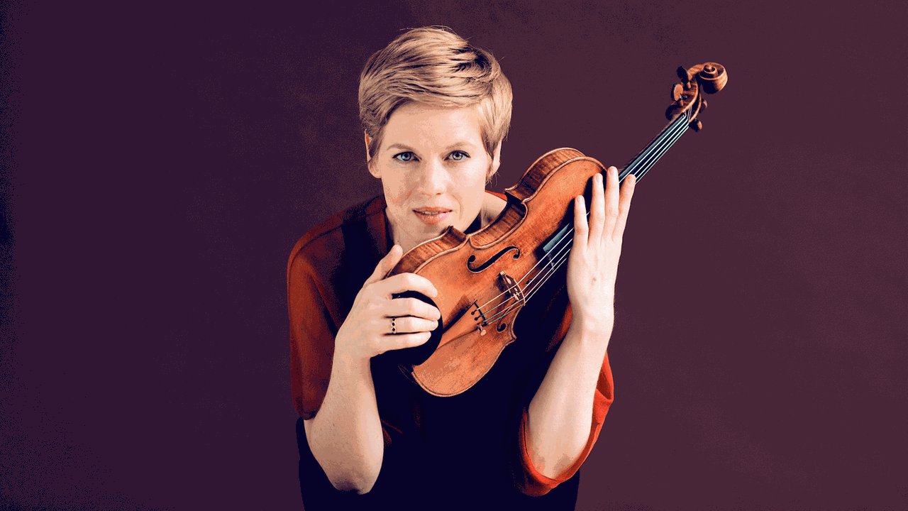 Eine Frau blickt in die Kamera, hält ihr Instrument, die Geige, vor sich Eine Frau blickt in die Kamera, hält ihr Instrument, die Geige, vor sich