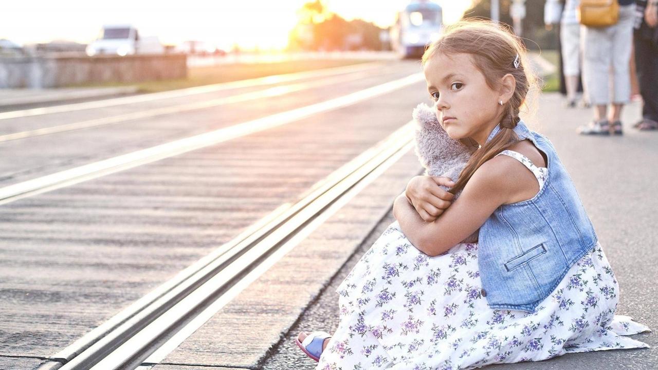 Ein Mädchen wartet mit seinem Kuscheltier am Bahnhof. Ein Mädchen wartet mit seinem Kuscheltier am Bahnhof.