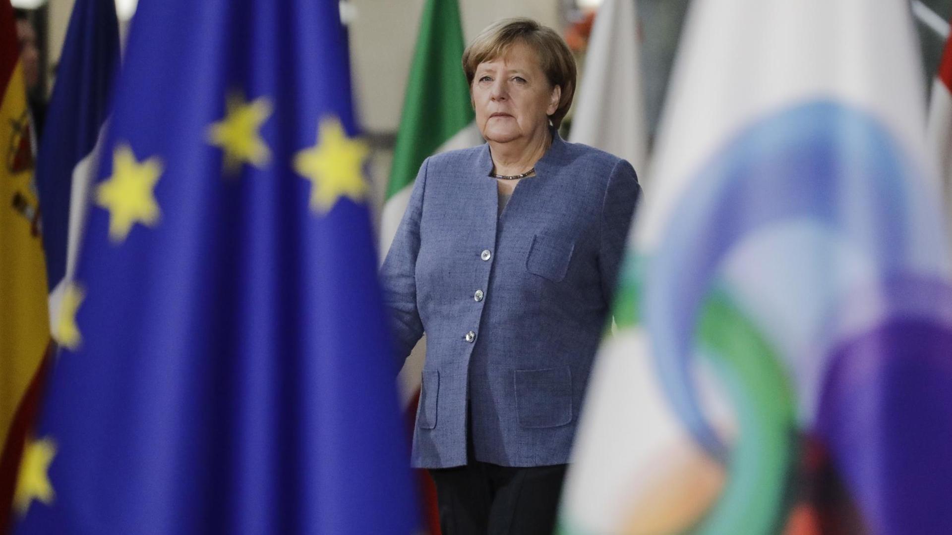 Angela Merkel beim Gipfeltreffen Östlichen Partnerschaft in Brüssel zwischen zwei Fahnen.