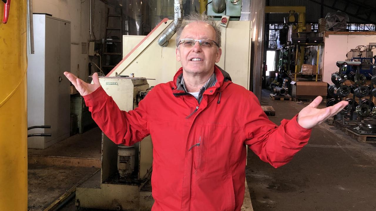 Mann in roter Jacke steht mitten in seinem Betrieb Mann in roter Jacke steht mitten in seinem Betrieb