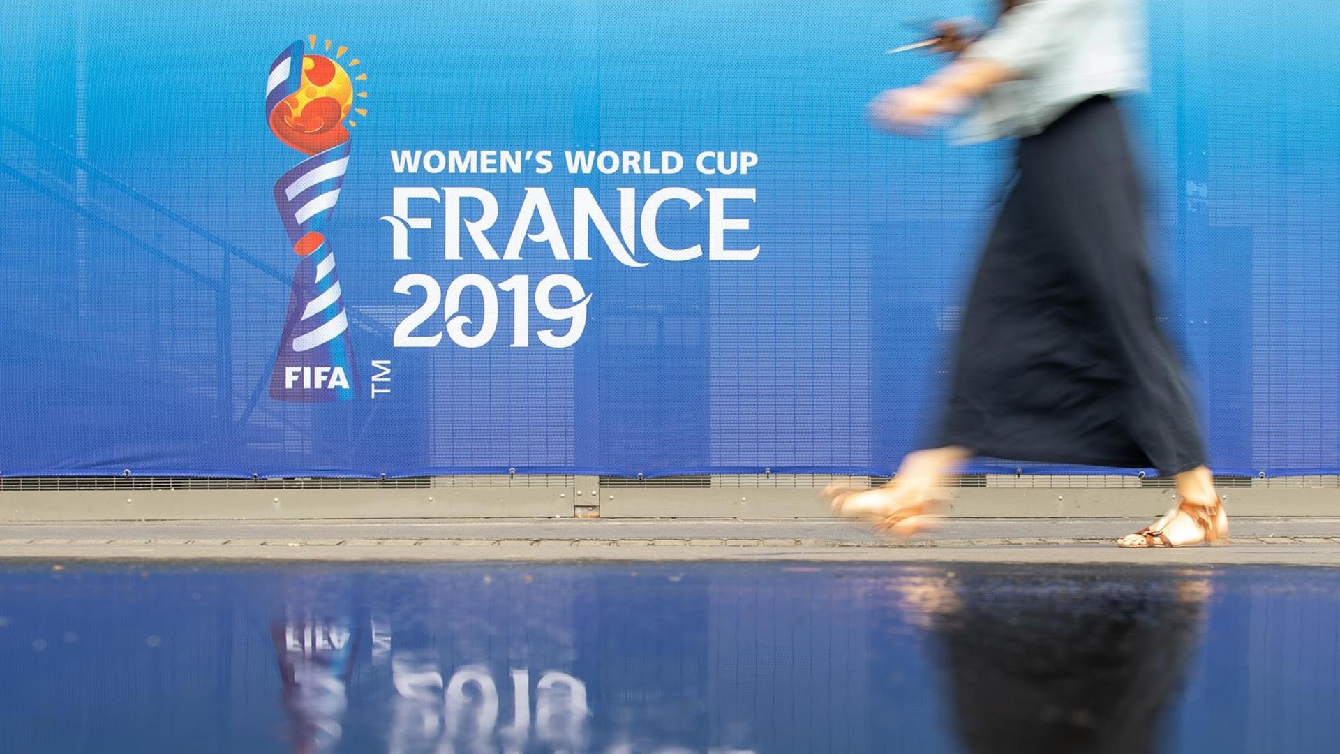 Eine Frau geht an einem Banner für die Fußball-Weltmeisterschaft der Frauen in Frankreich 2019 am Stadion Roazhon Park vorbei. Eine Frau geht an einem Banner für die Fußball-Weltmeisterschaft der Frauen in Frankreich 2019 am Stadion Roazhon Park vorbei.