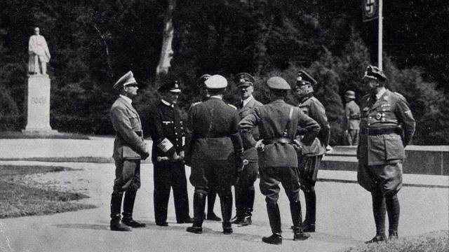 Hitler mit Offizieren im Jahr 1940 im Walv von Compiègne, in dem im Juni desselben Jahres der Waffenstillstand zwischen Frankreich und Deutschland geschlossen wurde, Schwarz-weiß-Aufnahme.