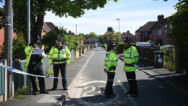 Polizisten im Stadtteil Fallowfield in Manchester an einer abgesperrten Straße, an der ein Haus durchsucht wurde.