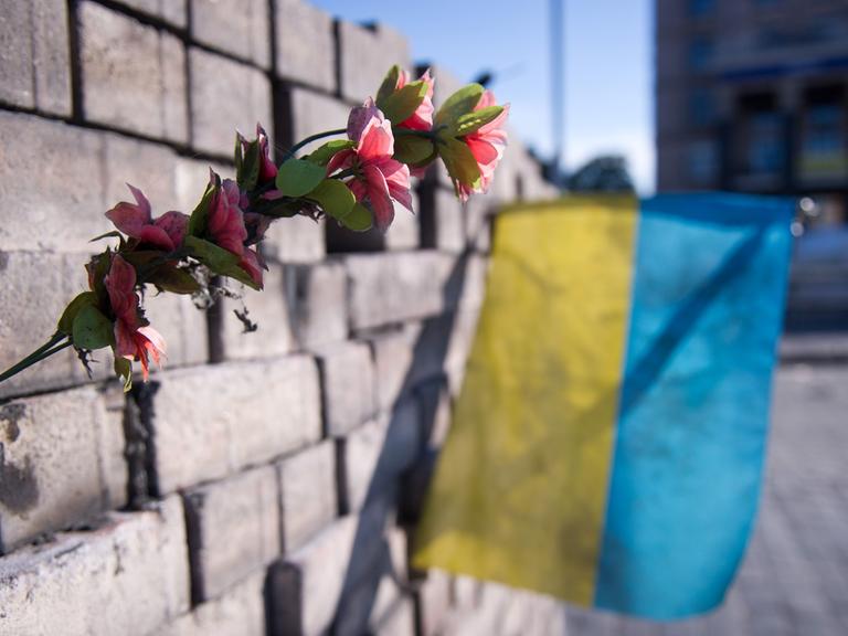 Kiew, Ukraine: Eine Blume und eine ukrainische Flagge auf dem Maidan in einer Barrikade