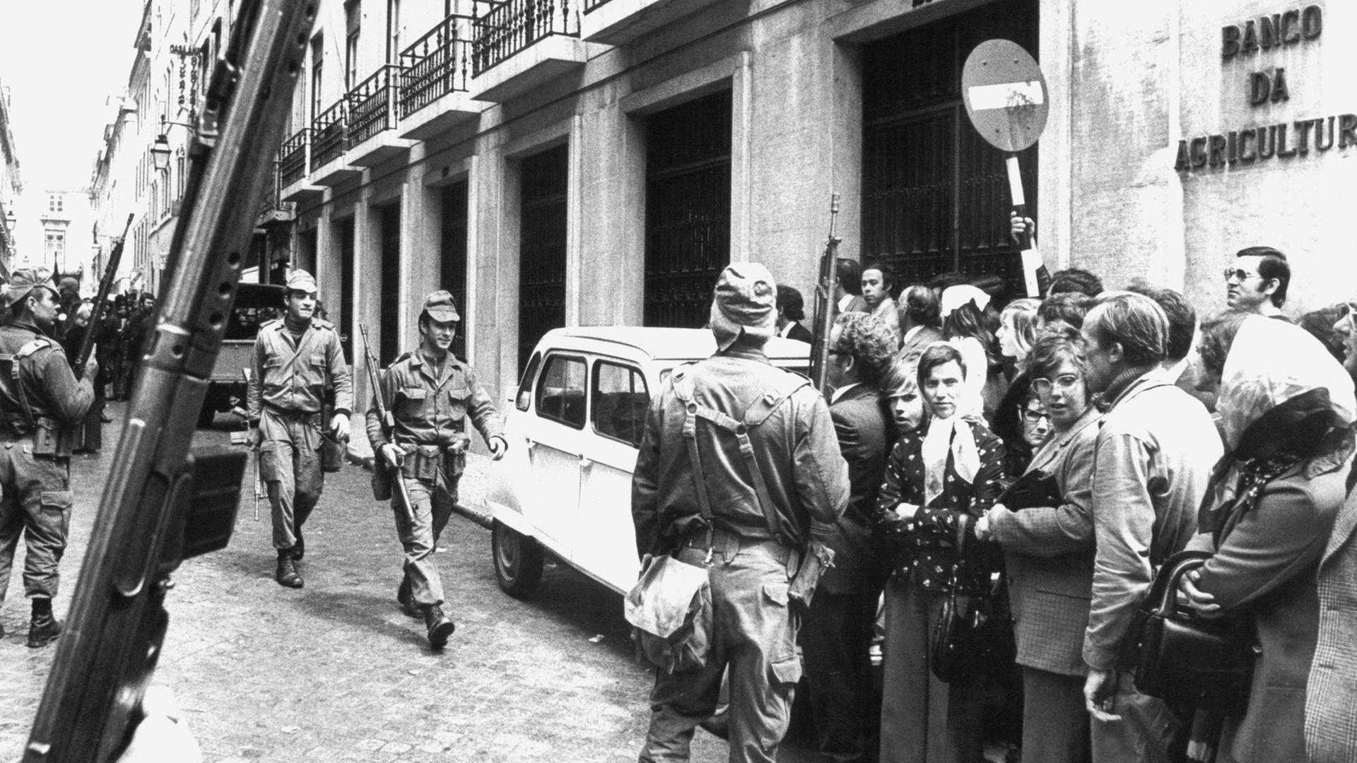 Soldaten sorgen am 29. April 1974 vor einem Bankgebäude in Lissabon für Ordung. Bei dem friedlichen Militärputsch vom 25. April 1974 wurde das diktatorische Regime Marcelo Caetano von oppositionellen Offizieren gestürzt. Portugals Befreiung von der Diktatur ging als "Nelkenrevolution" in die Geschichtsbücher ein.