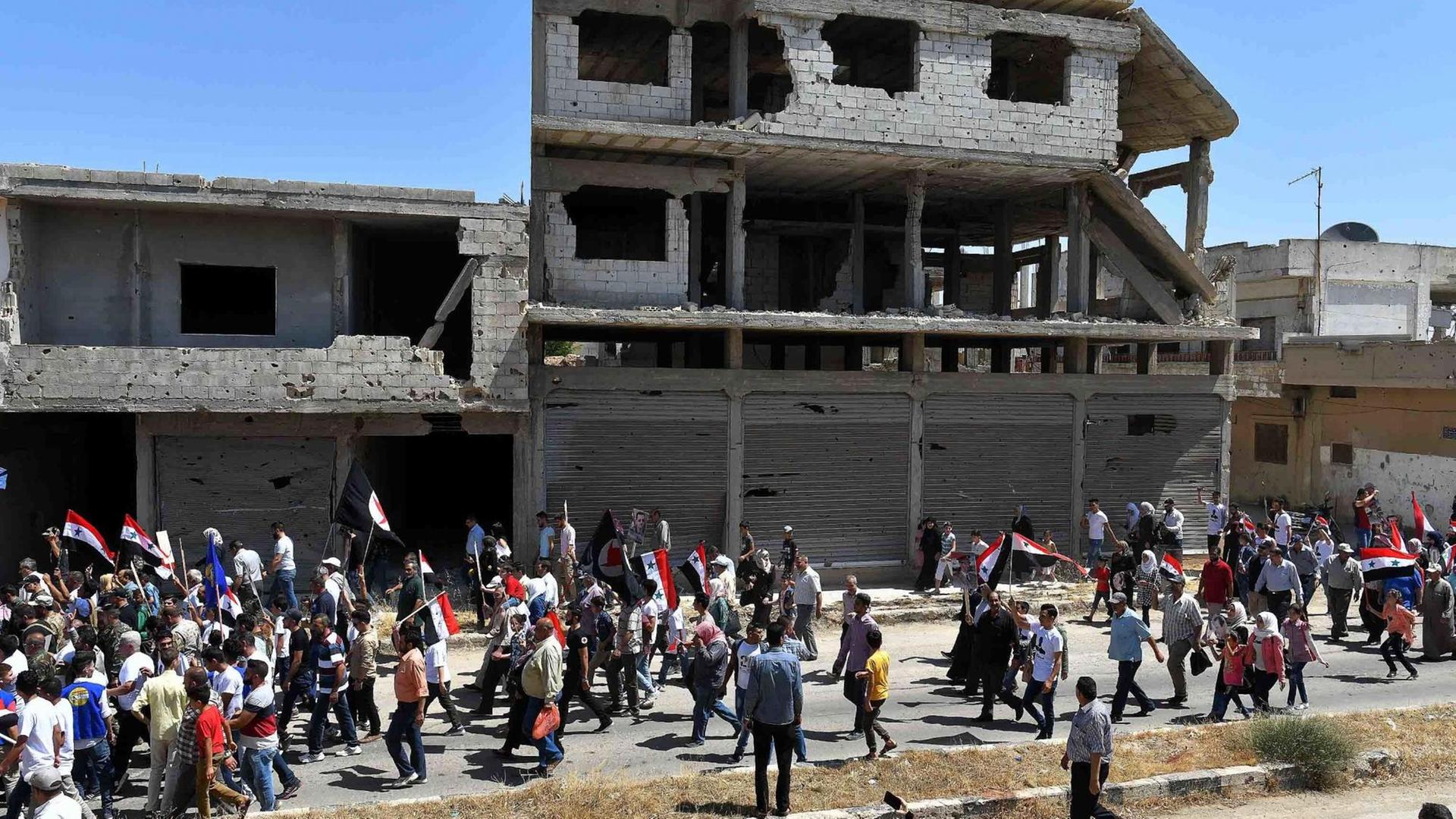 Syrische Zivilisten gehen am 7. Juli 2019 in die Stadt Al Qusayr in der Provinz Homs Syrische Zivilisten gehen am 7. Juli 2019 in die Stadt Al Qusayr in der Provinz Homs