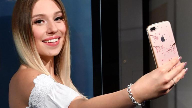 YouTuberin Bianca "Bibi" Heinicke posiert mit einem Smartphone