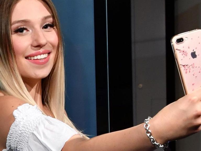 YouTuberin Bianca "Bibi" Heinicke posiert mit einem Smartphone