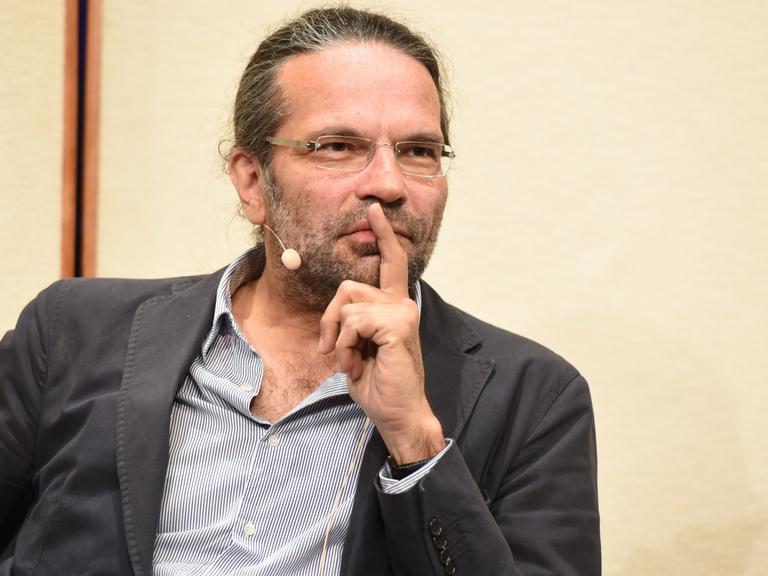 Der Philosoph Robert Pfaller spricht an einem Redepult.