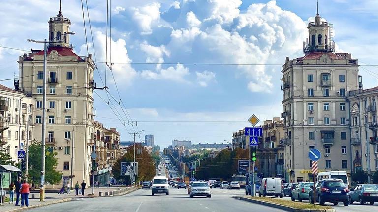 In der Innenstadt von Saporischschja warten Autos an einer Ampelkreuzung. Links ist eine Oberleitung für eine Straßenbahn. Wolken sind am Himmel. In der Innenstadt von Saporischschja warten Autos an einer Ampelkreuzung. Links ist eine Oberleitung für eine Straßenbahn. Wolken sind am Himmel.