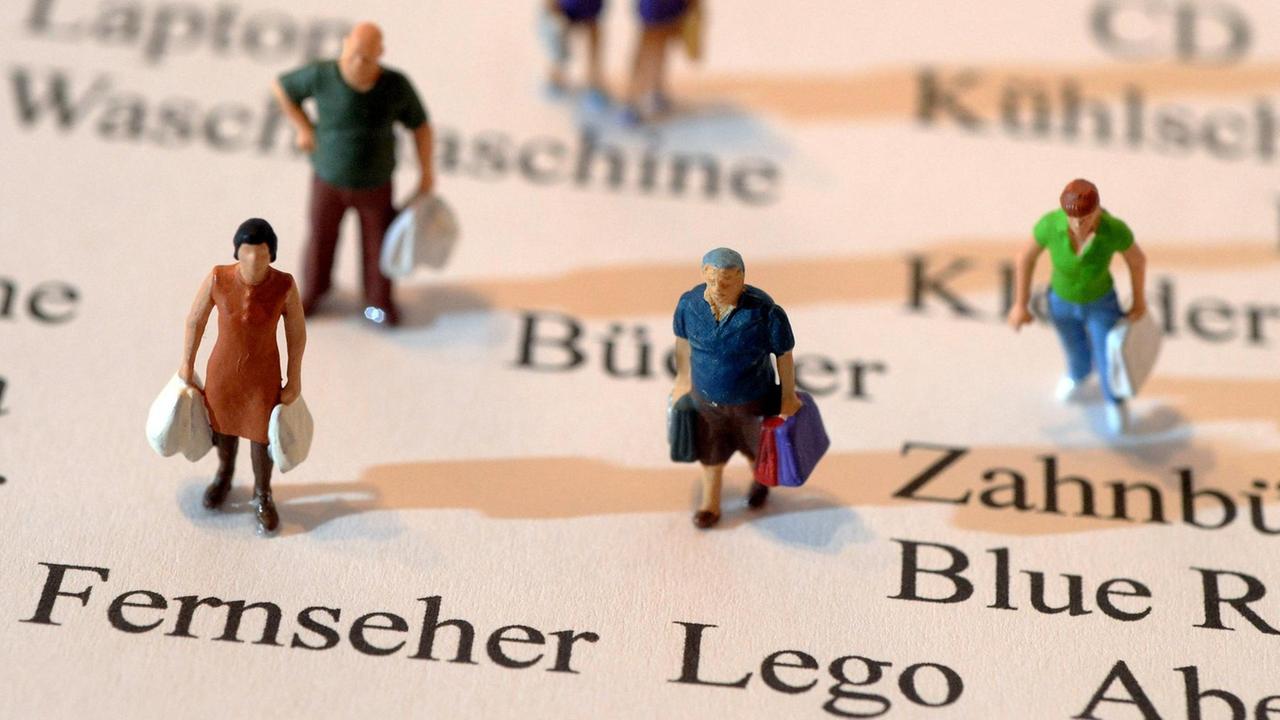 Miniatur-Figuren, die Einkaufstüten in Händen halten Miniatur-Figuren, die Einkaufstüten in Händen halten