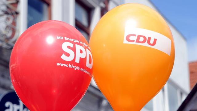 Ein SPD- und ein CDU- Luftballon schweben in der Innenstadt.