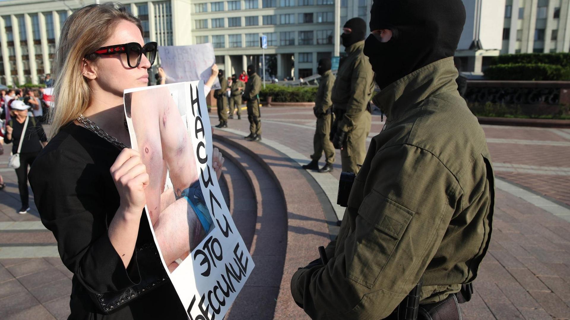 Eine mutige junge Frau steht vor einem Polizisten während der Proteste in Minsk gegen den Präsidenten Lukaschenko. Sie konfrontiert ihn mit einem Plakat, auf dem Wunden eines von der Polizei malträtierten Demonstranten zu sehen sind. Auf dem Plakat steht auf belarussisch: Gewalt ist Schwäche. Eine mutige junge Frau steht vor einem Polizisten während der Proteste in Minsk gegen den Präsidenten Lukaschenko. Sie konfrontiert ihn mit einem Plakat, auf dem Wunden eines von der Polizei malträtierten Demonstranten zu sehen sind. Auf dem Plakat steht auf belarussisch: Gewalt ist Schwäche.