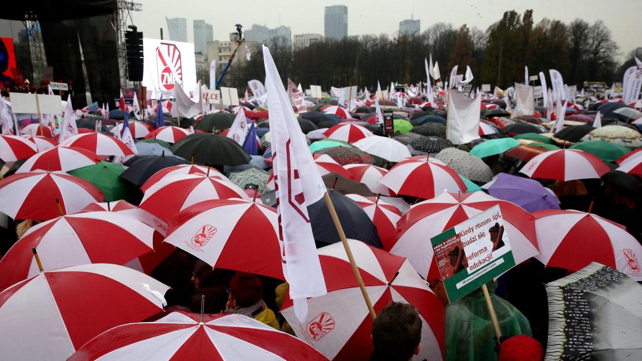 Sie sehen viele rot-weiße Regenschirme von Teilnehmern der Demonstration. Sie sehen viele rot-weiße Regenschirme von Teilnehmern der Demonstration.