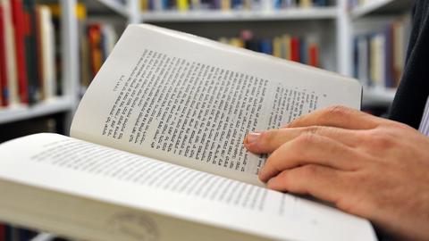 Ein Mann blättert in einem Buch in hebräischer Sprache.