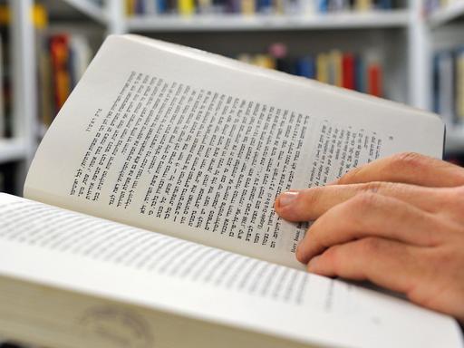 Ein Mann blättert in einem Buch in hebräischer Sprache.