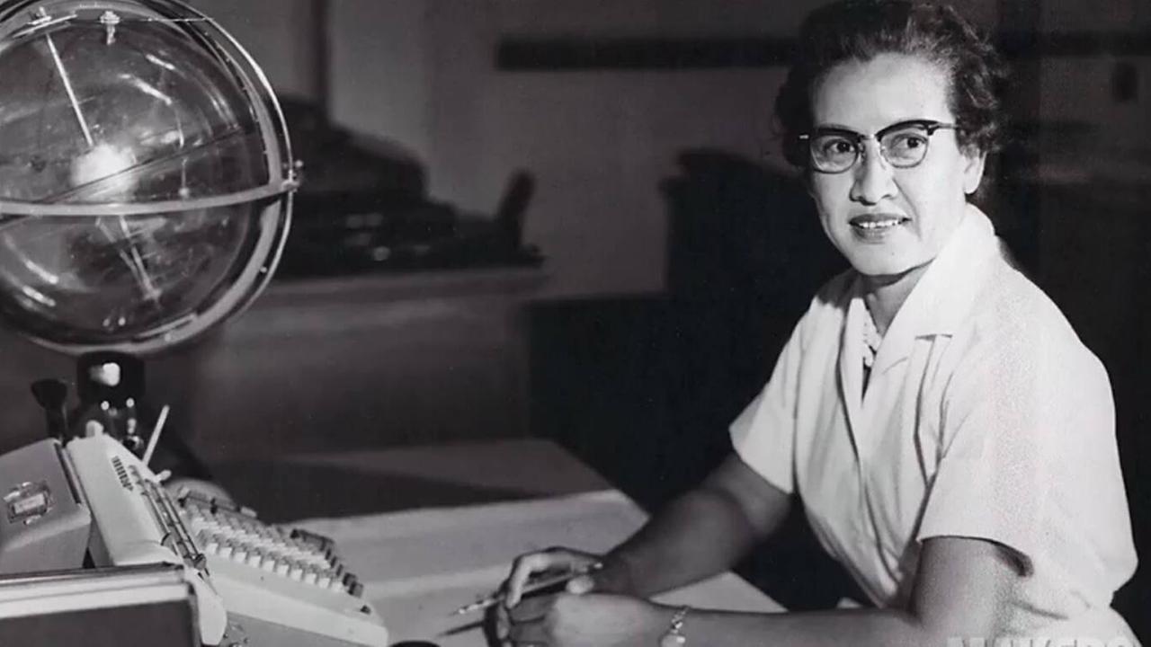 Die Mathematikerin Katherine sitzt an ihrem Schreibtisch, vor ihr eine Schreibmaschine und ein Globus. Schwarz-weiß Bild.