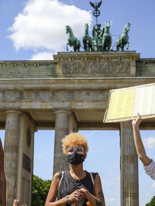 Aktivisten vor dem Brandenburger Tor halten ein Schild mit der Aufschrift "Say Their Names" in die Höhe.