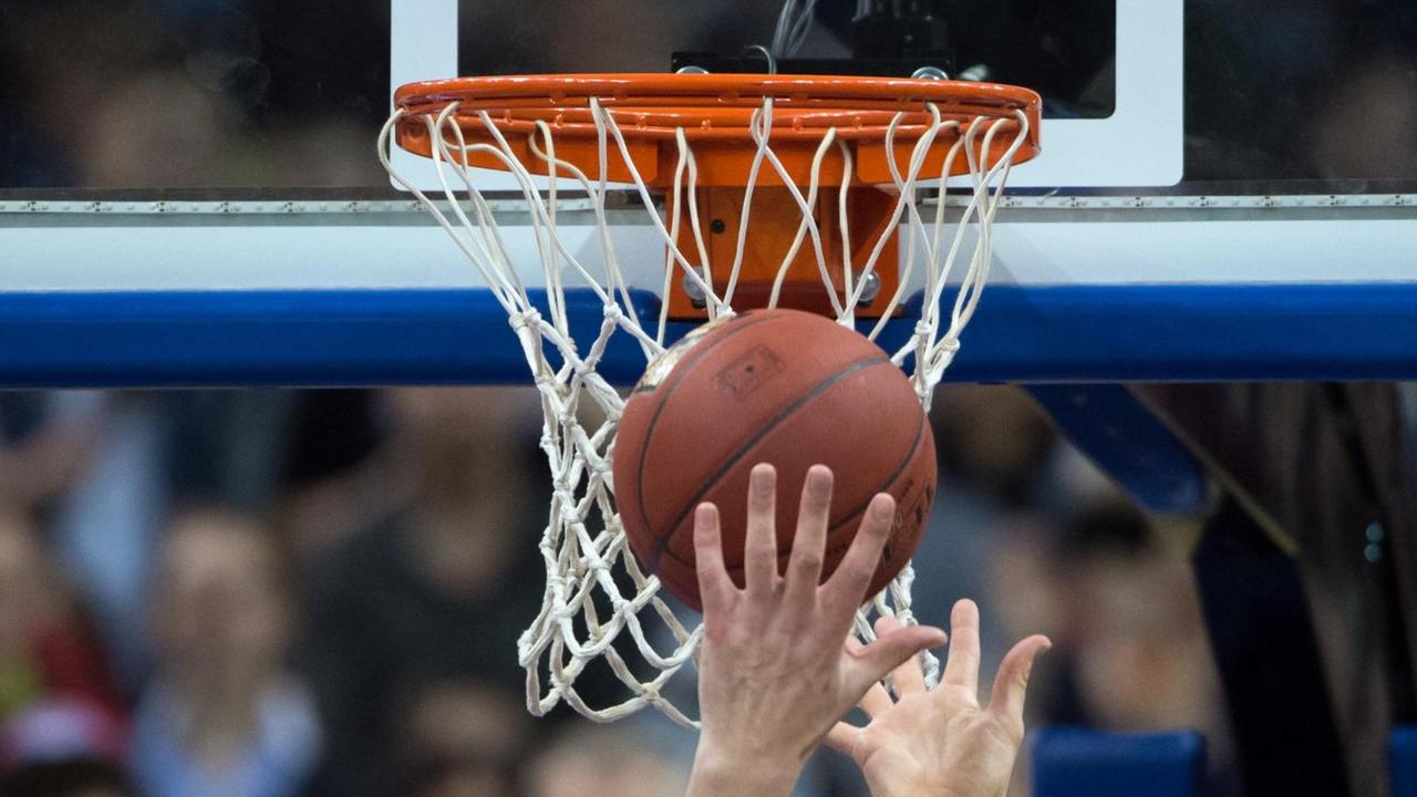 Hände recken sich unter einem Basketballkorb nach dem Ball. Hände recken sich unter einem Basketballkorb nach dem Ball.