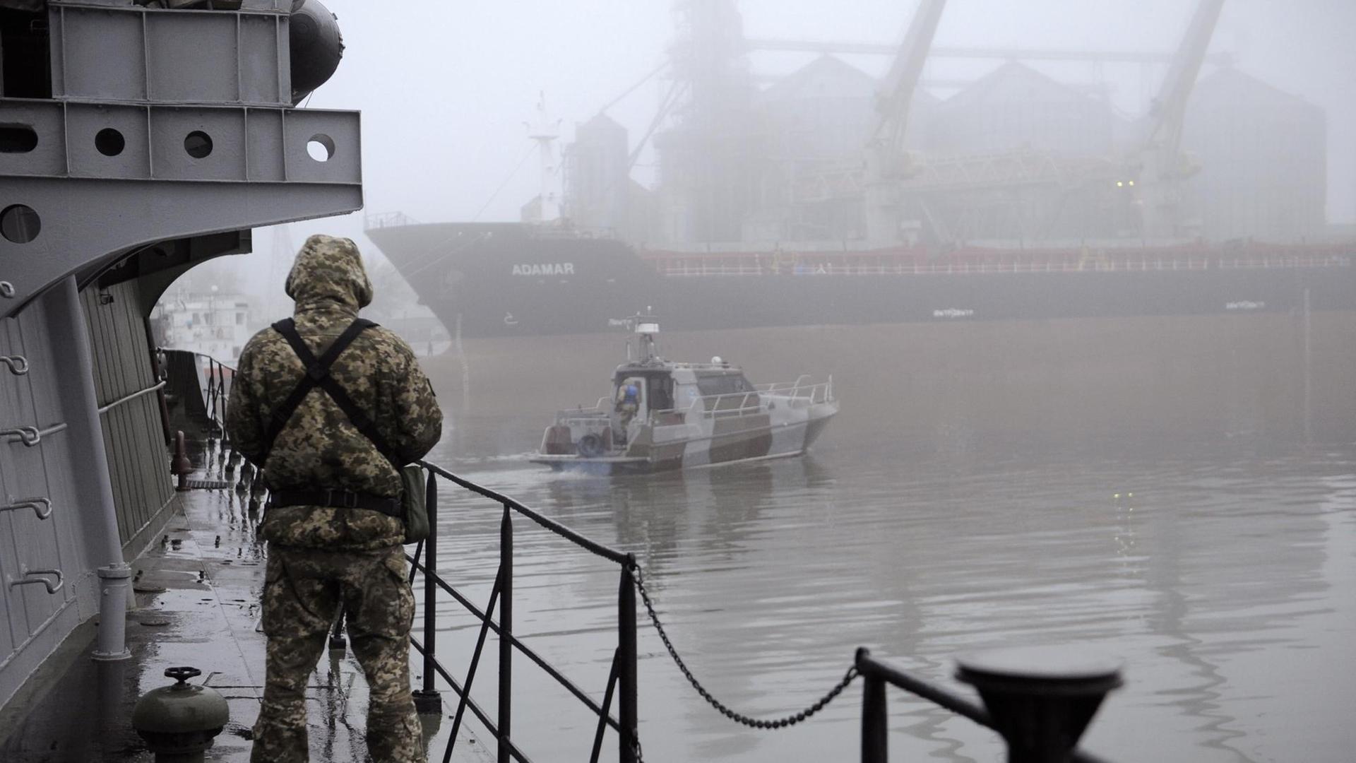 Der Soldat im Tarn-Anzug steht im Hafen auf dem Schiff. Der Soldat im Tarn-Anzug steht im Hafen auf dem Schiff.