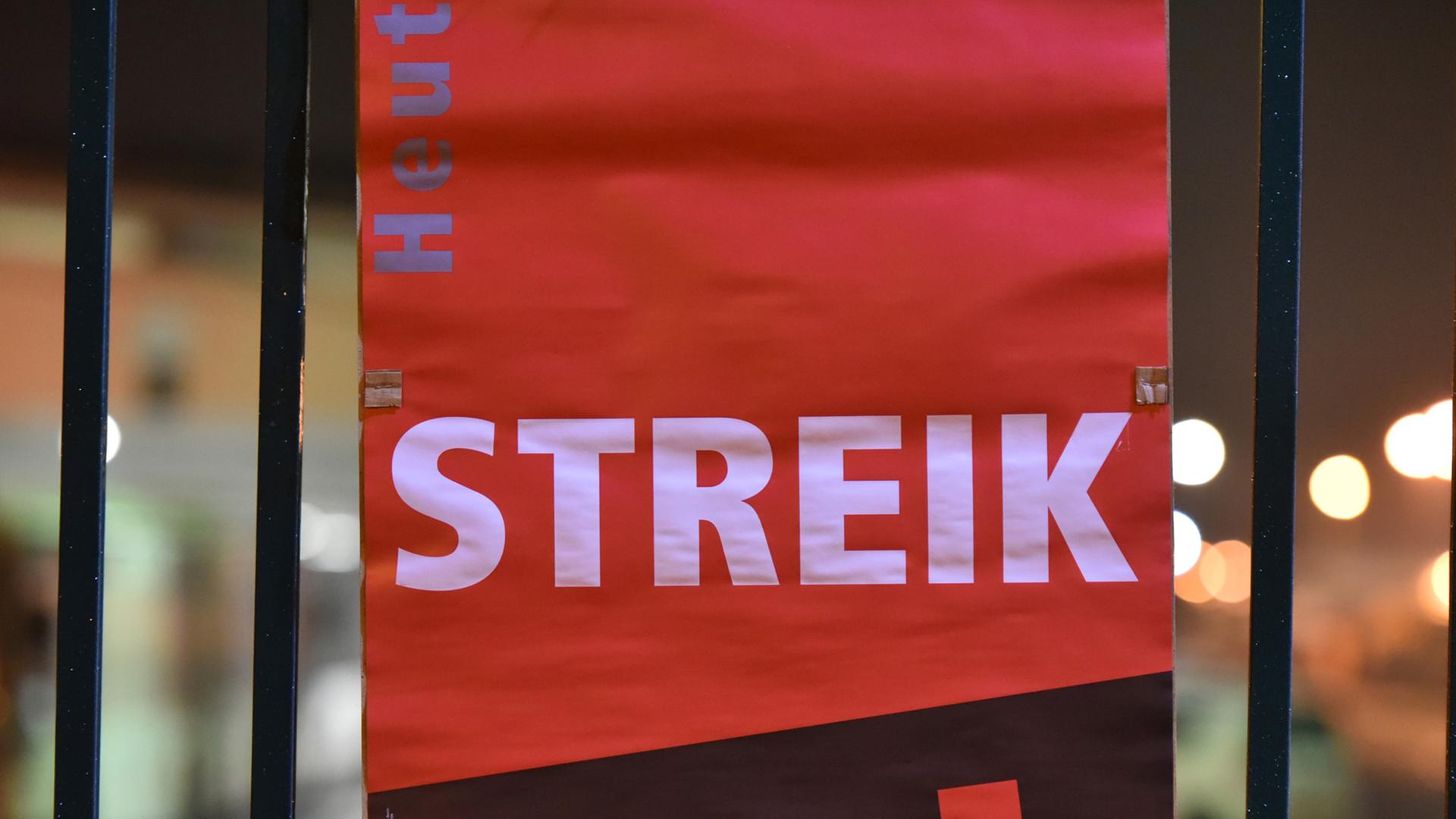 Ein Verdi-Plakat mit dem Text "Streik" hängt an einem Metallzaun.