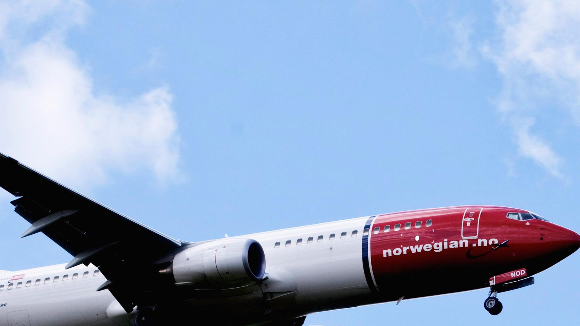 Eine Boeing 737-800 des Billig-Fliegers Norwegian Air Shuttle fliegt vor blauem Himmel