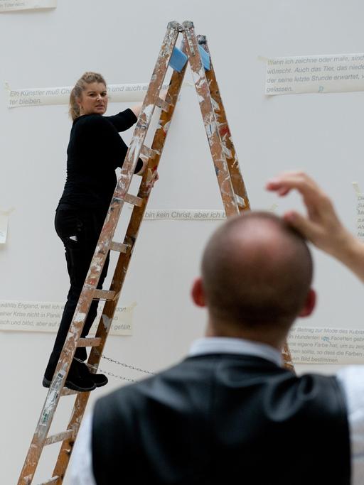 Zwei Mitarbeiter des Kunstmuseums bringen am 23.04.2014 in Wolfsburg (Niedersachsen) in der Ausstellung des Malers Oskar Kokoschka Zitate an einer weißen Wand an.