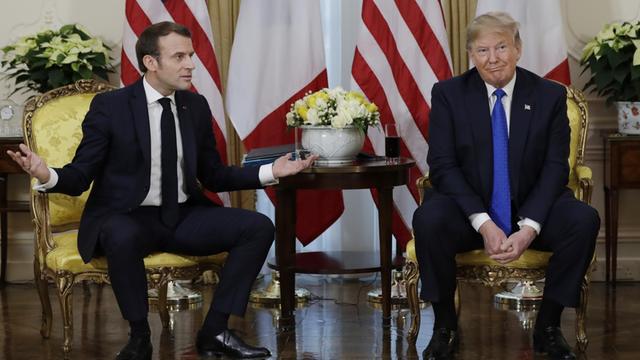US-Präsident Donald Trump und Frankreichs Staatschef Emmanuel Macron sitzen nebeneinander. Macron gestikuliert und Trump schaut ratlos.