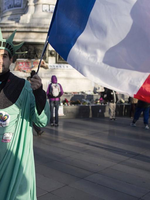 Ein Mann ist verkleidet als Freiheitsstatue und hält die französische Flagge in der Hand - er nimmt am Trauermarsch wegen des Anschlags gegen die Redaktion der Satirezeitschrift "Charlie Hebdo" in Paris am 11.01.2014 teil